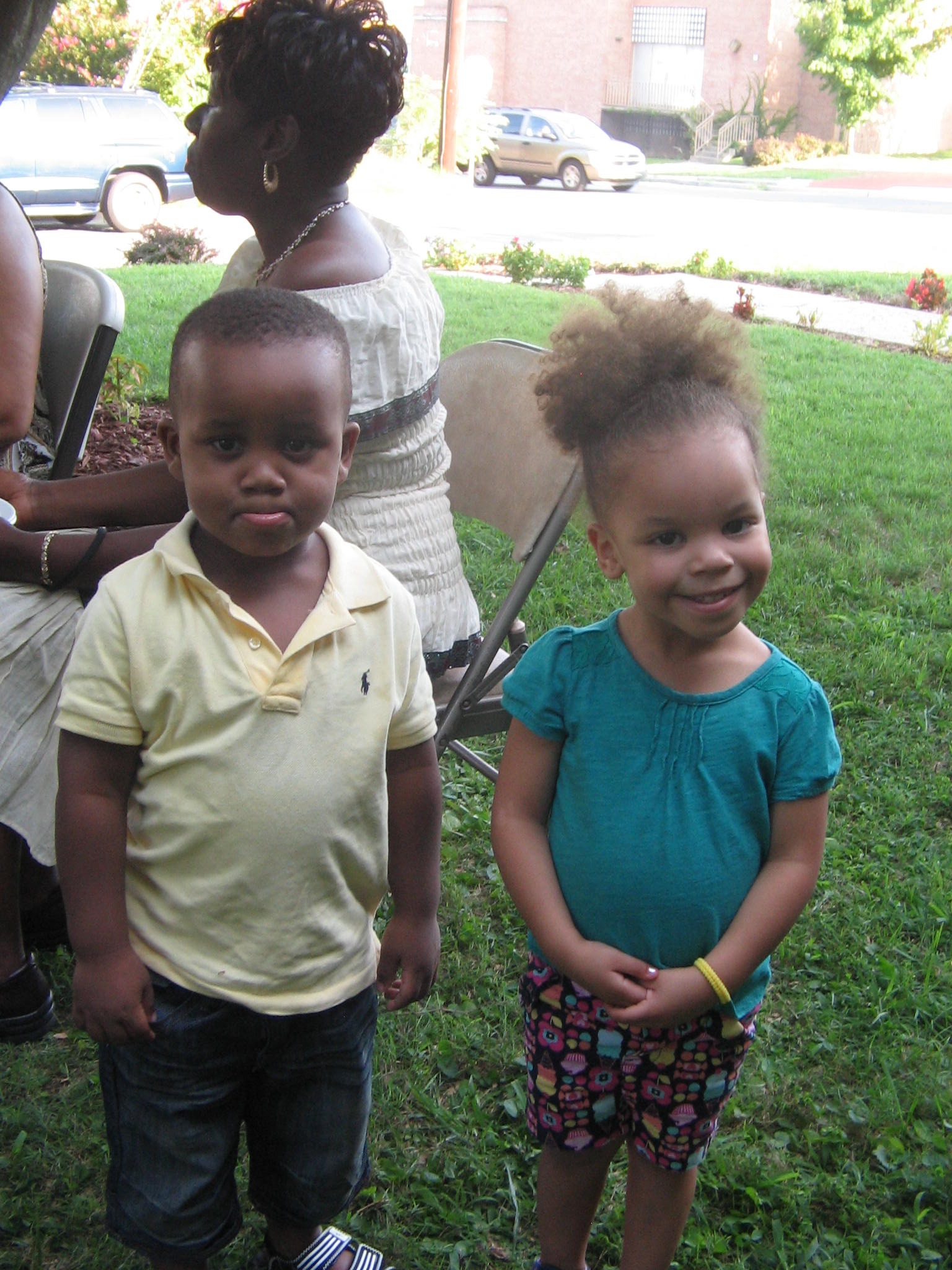 Children standing outdoors on a lawn near a building
